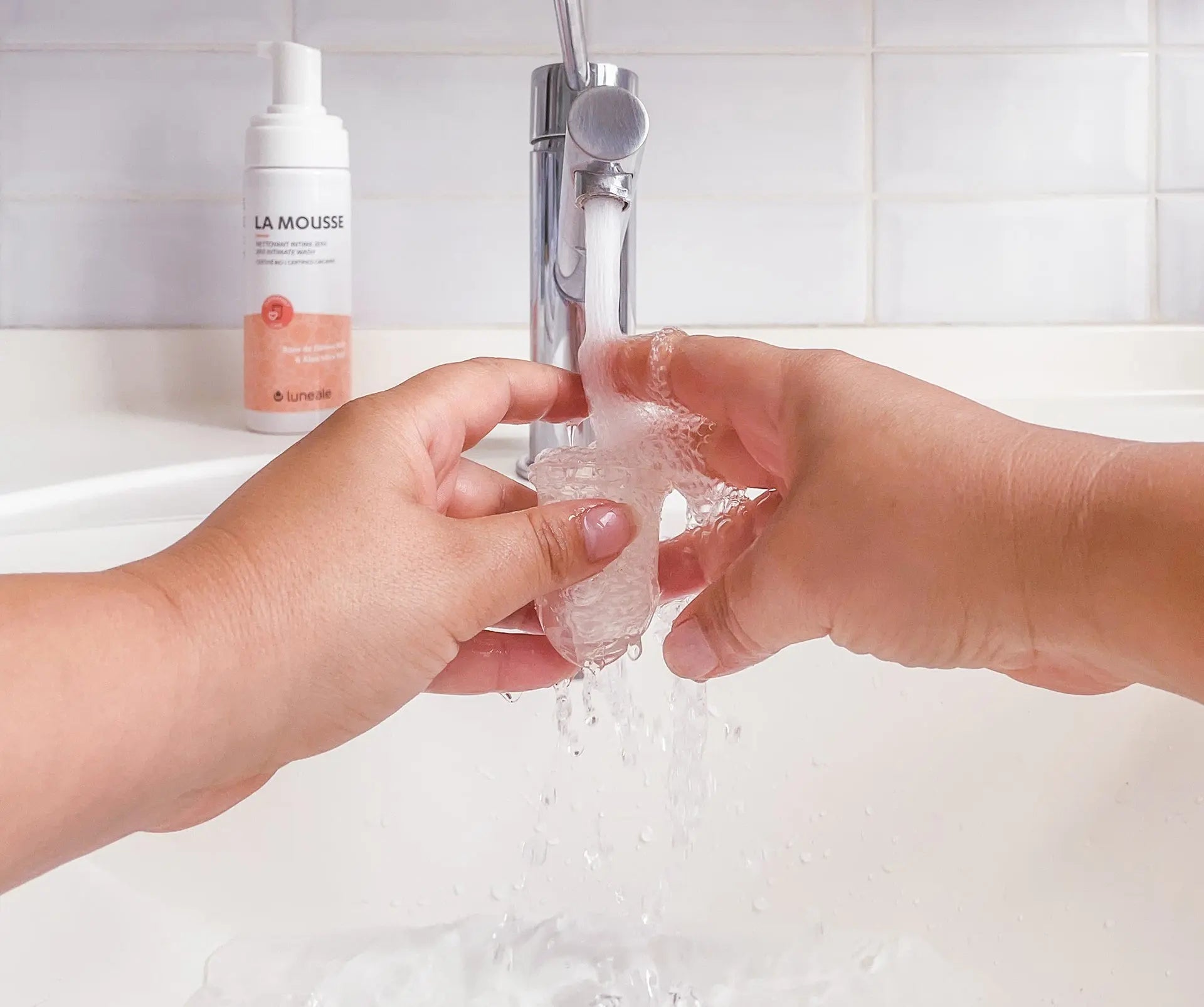 Personne rinçant sa cup menstruelle sous l'eau du robinet pour la nettoyer pendant les règles