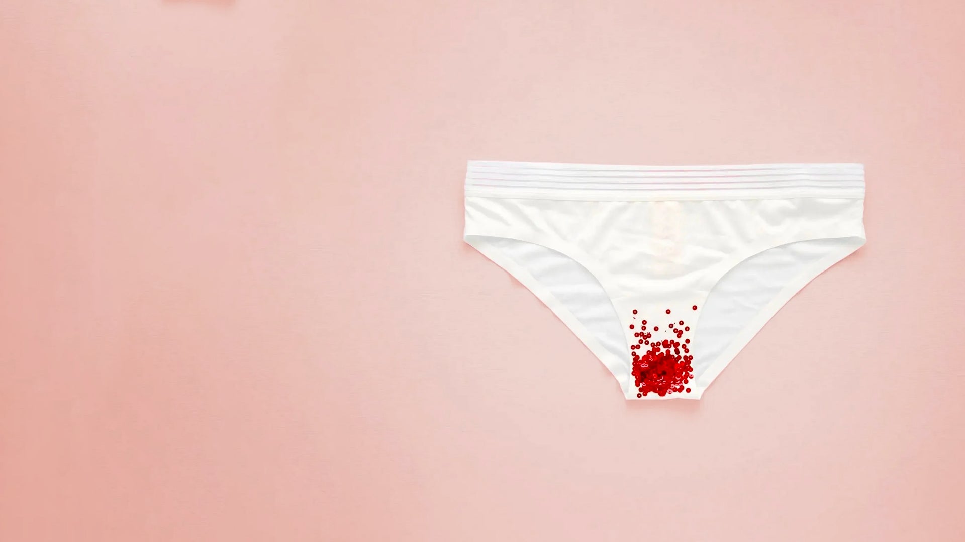 Culotte menstruelle blanche avec des sequins rouges représentant le sang des règles illustrant un article sur la composition du sang des regles Image