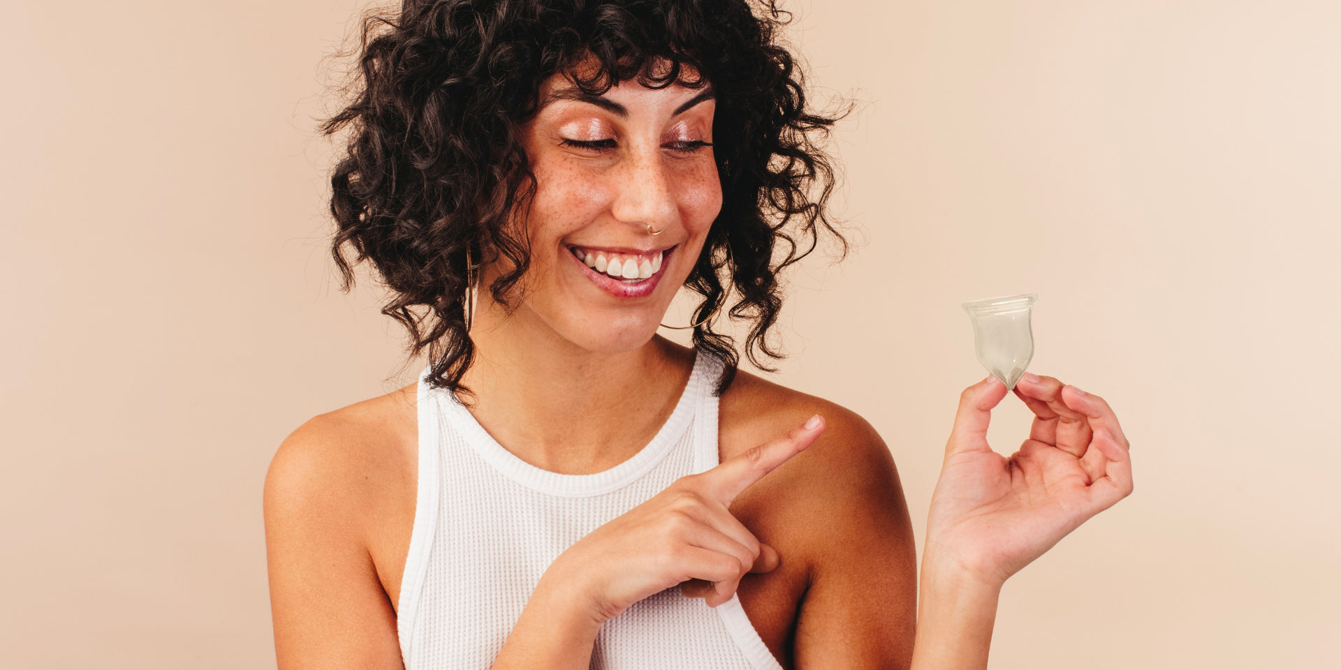 femme qui tient une cup menstruelle Luneale dans une main et la pointe du doigt de l'autre